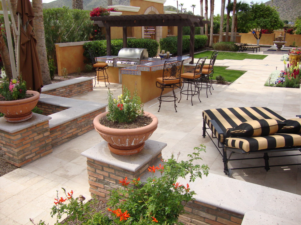 Inspiration for a mid-sized mediterranean backyard patio in Phoenix with an outdoor kitchen, tile and a pergola.
