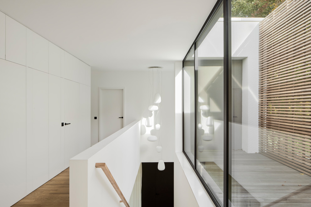 Diseño de recibidores y pasillos actuales con paredes blancas, suelo de madera clara y madera