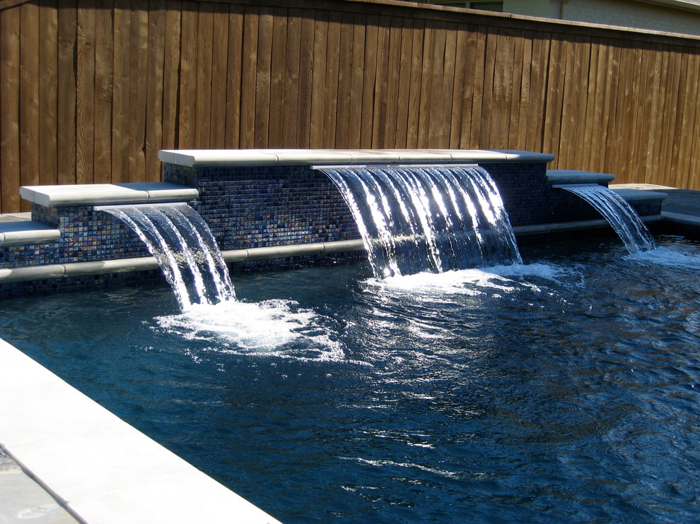 Immagine di una piscina design a "L" di medie dimensioni e dietro casa con una vasca idromassaggio e lastre di cemento