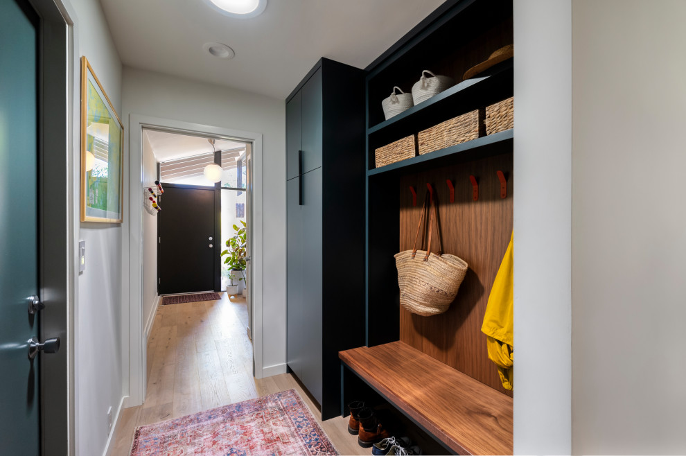 Foto di un piccolo corridoio minimalista con pareti bianche, parquet chiaro, una porta singola, una porta nera e pavimento marrone