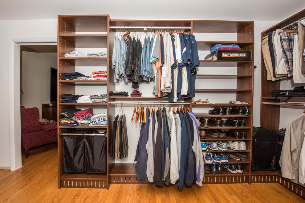 Photo of a large arts and crafts gender-neutral walk-in wardrobe in Other with open cabinets, brown cabinets and brown floor.