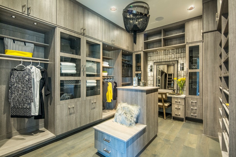 This is an example of a large transitional gender-neutral walk-in wardrobe in San Diego with flat-panel cabinets, grey cabinets, beige floor and medium hardwood floors.
