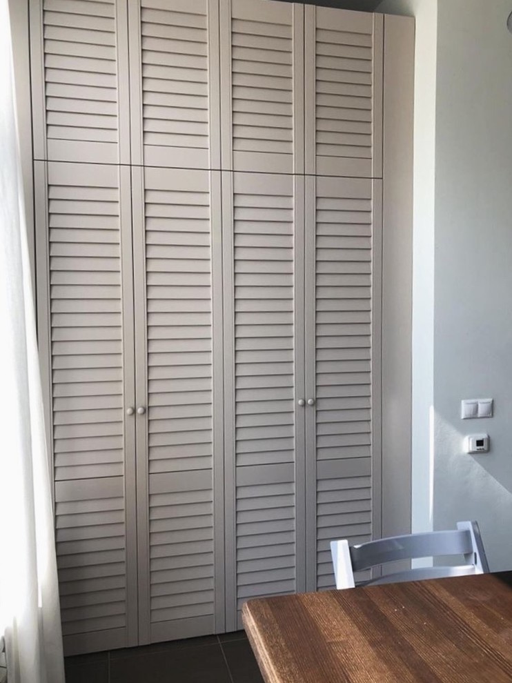 This is an example of a mid-sized transitional built-in wardrobe in Other with louvered cabinets and beige cabinets.