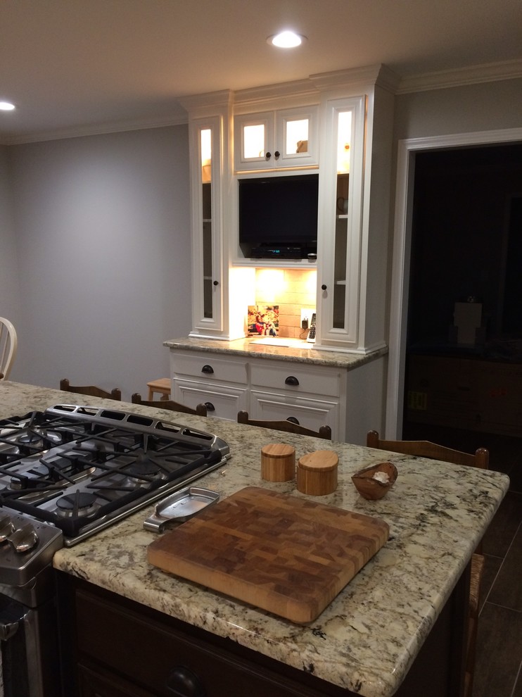 Eat-in kitchen - large transitional l-shaped brown floor eat-in kitchen idea in Birmingham with a farmhouse sink, recessed-panel cabinets, white cabinets, beige backsplash, stainless steel appliances and an island