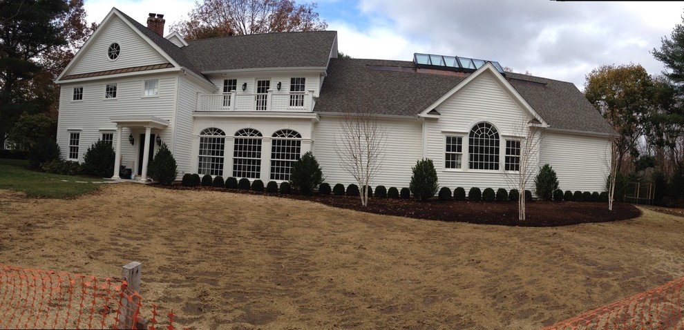 Large traditional two-storey white house exterior in New York with vinyl siding, a gable roof and a shingle roof.