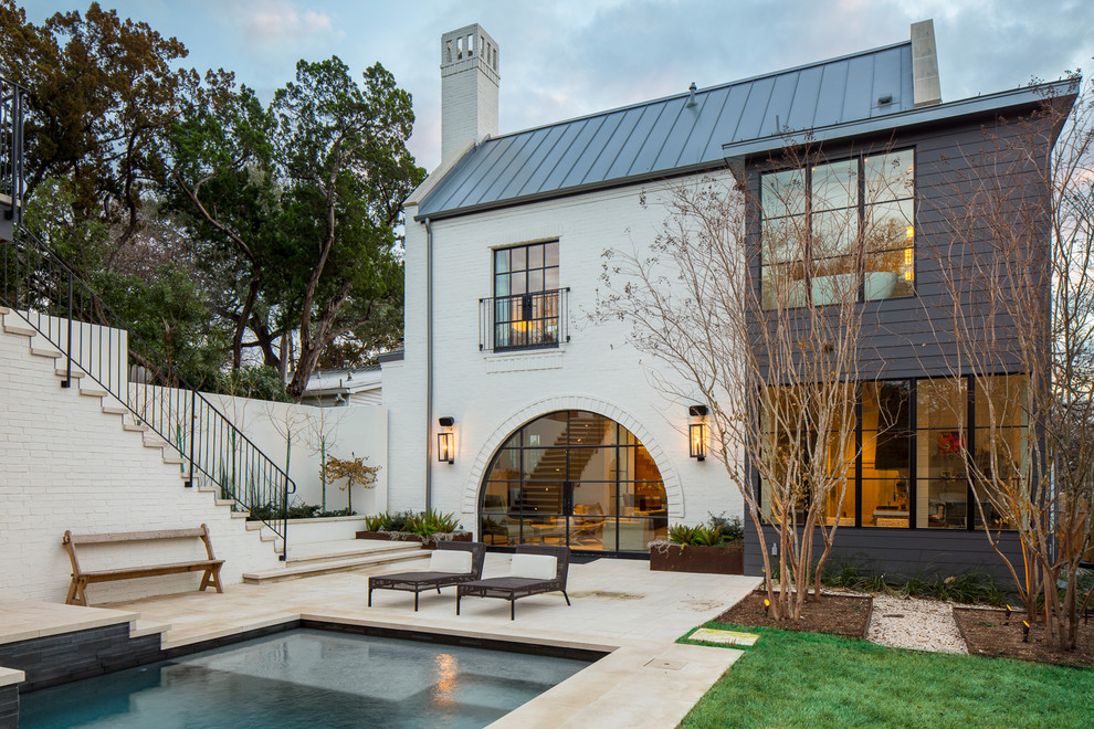 This is an example of a transitional two-storey white house exterior in Austin with mixed siding, a hip roof and a metal roof.