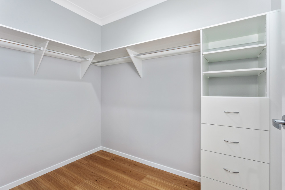 Photo of a small contemporary gender-neutral walk-in wardrobe in Brisbane with vinyl floors and brown floor.