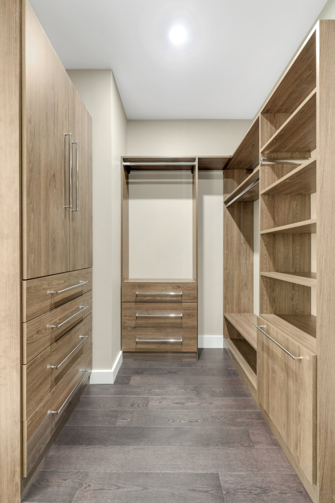 Ejemplo de armario y vestidor unisex minimalista grande con a medida, armarios con paneles lisos, puertas de armario marrones y suelo de madera oscura