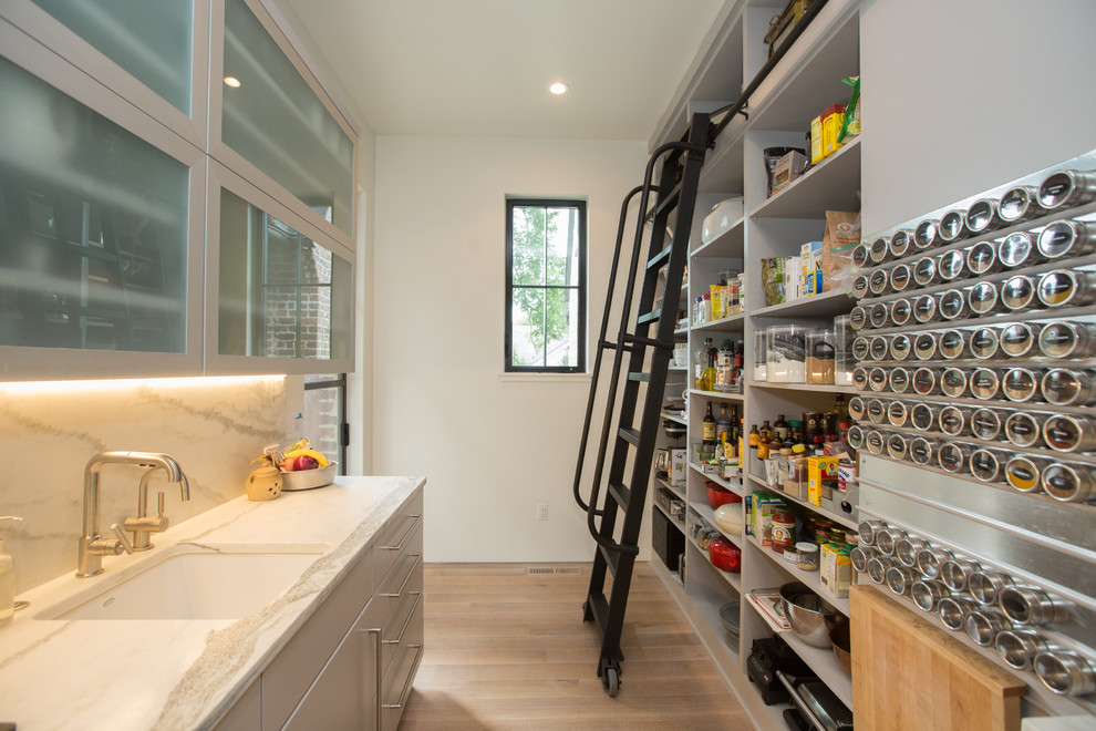 Inspiration for a transitional galley kitchen pantry in Other with an undermount sink, flat-panel cabinets, grey cabinets, white splashback, light hardwood floors, beige floor and white benchtop.