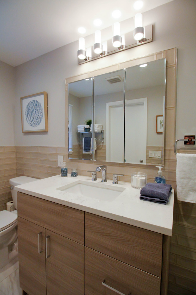 Photo of a mid-sized contemporary master bathroom in Newark with flat-panel cabinets, medium wood cabinets, an alcove shower, a two-piece toilet, beige tile, porcelain tile, beige walls, porcelain floors, an undermount sink, engineered quartz benchtops, white floor, a hinged shower door, white benchtops, a single vanity and a freestanding vanity.