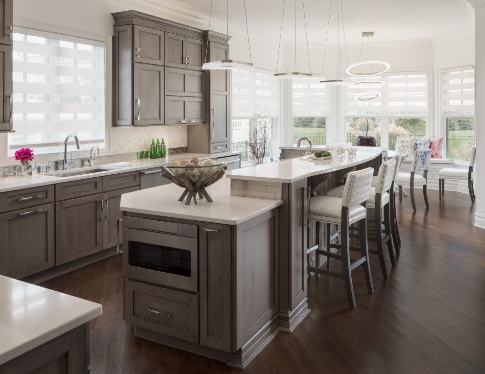 Huge transitional l-shaped brown floor and dark wood floor eat-in kitchen photo in Newark with an undermount sink, shaker cabinets, medium tone wood cabinets, quartz countertops, white backsplash, mosaic tile backsplash, stainless steel appliances, an island and white countertops