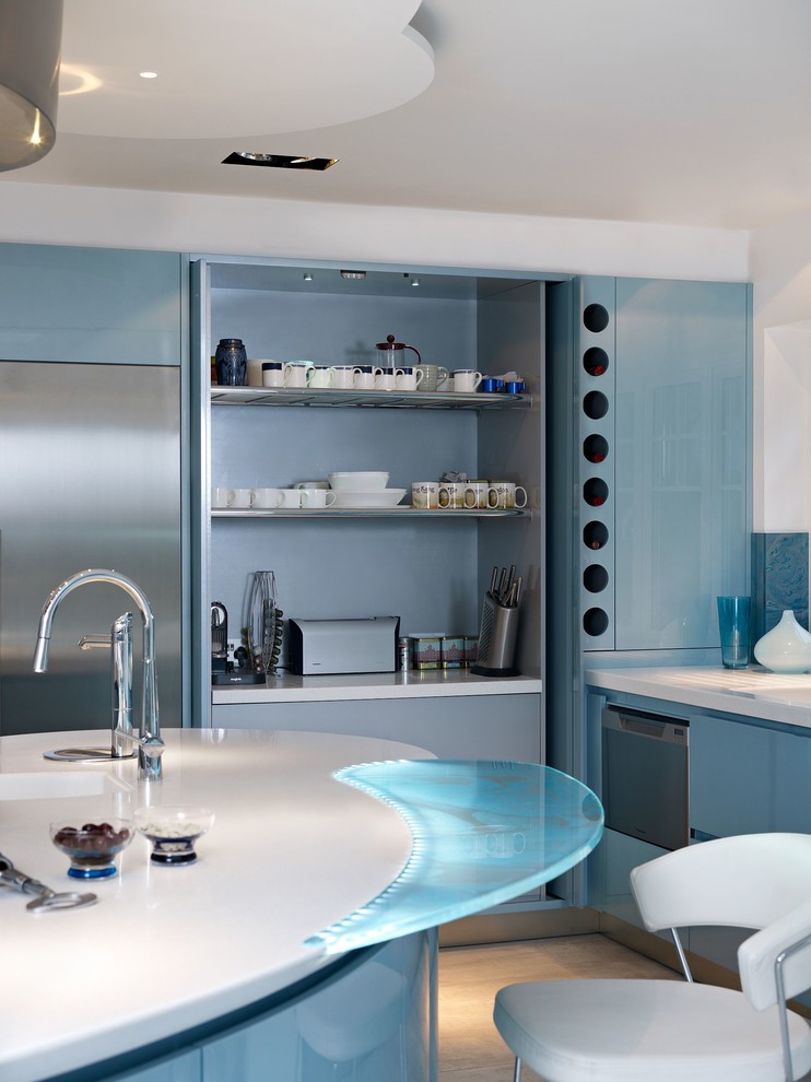 This is an example of an expansive modern u-shaped eat-in kitchen in London with an integrated sink, flat-panel cabinets, blue cabinets, solid surface benchtops, blue splashback, glass sheet splashback, stainless steel appliances, marble floors and with island.
