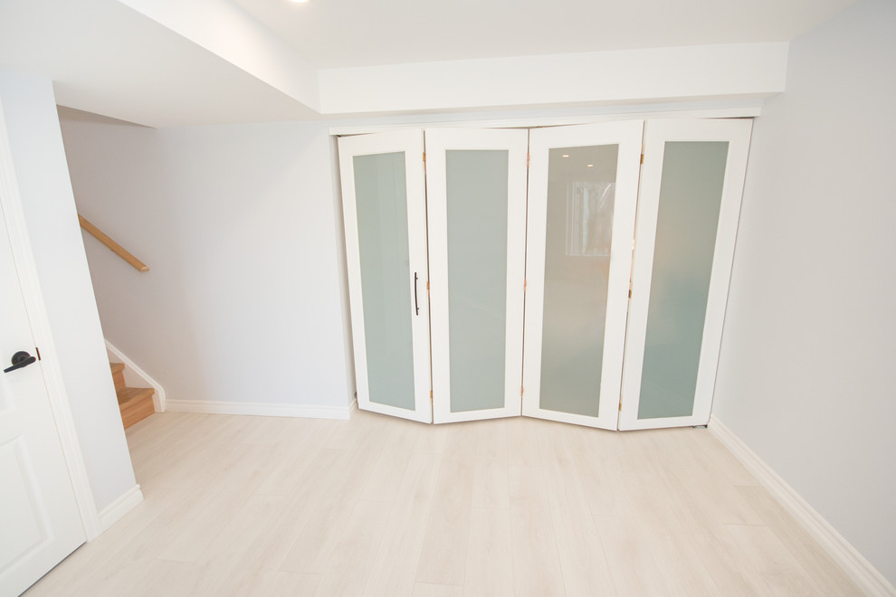Photo of a mid-sized contemporary walk-out basement in Toronto with white walls, laminate floors, no fireplace and white floor.
