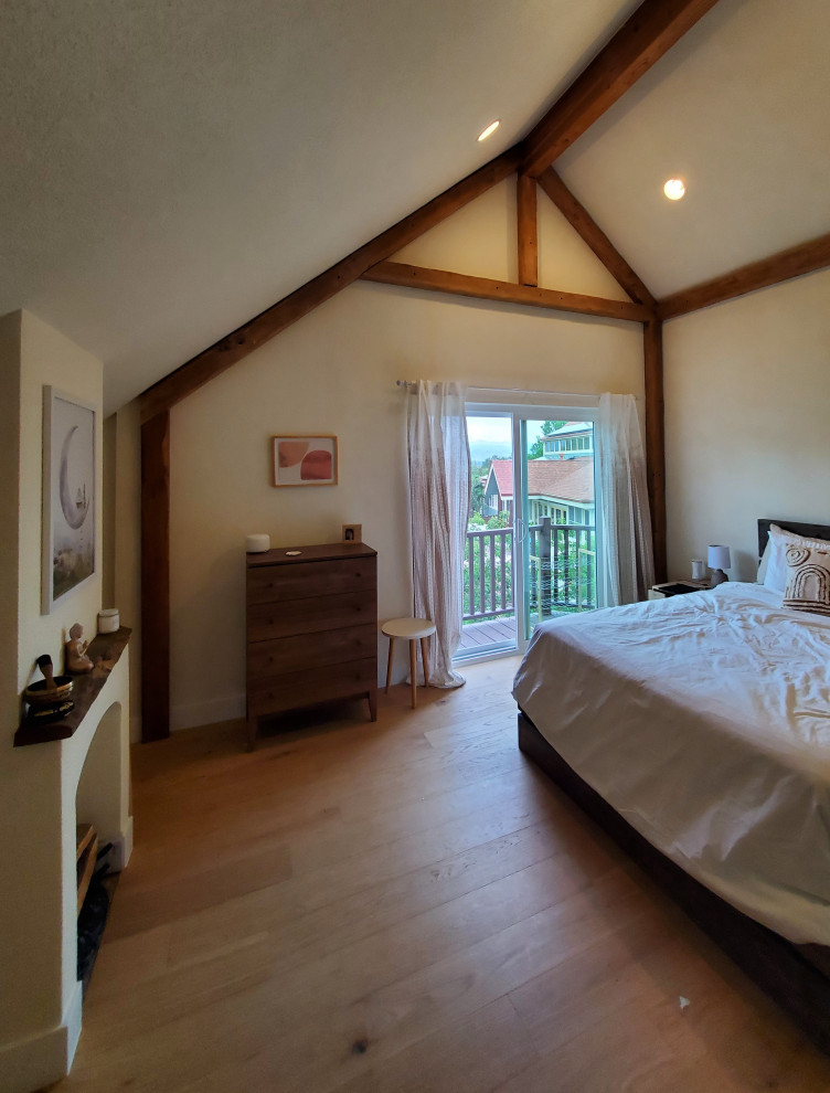 Mid-sized mediterranean master bedroom in Denver with beige walls, medium hardwood floors, a standard fireplace, a plaster fireplace surround, brown floor, exposed beam and wood walls.