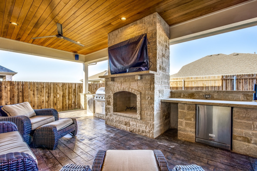 Mid-sized eclectic backyard patio in Dallas with with fireplace, stamped concrete and a roof extension.