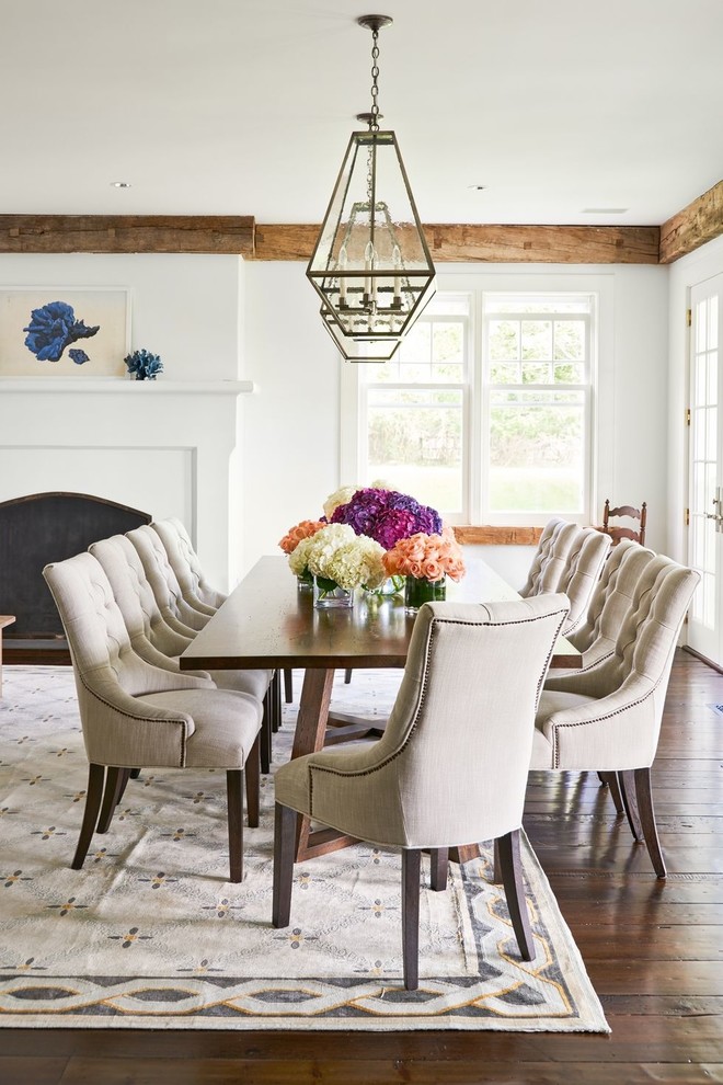 Design ideas for a country dining room in Los Angeles with white walls, dark hardwood floors, a standard fireplace and brown floor.