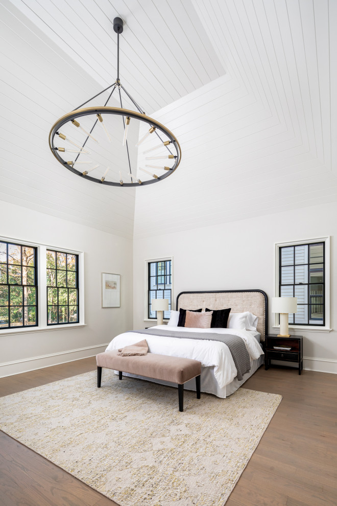 Large modern master bedroom in Charlotte with white walls, light hardwood flooring, brown floors and a vaulted ceiling.