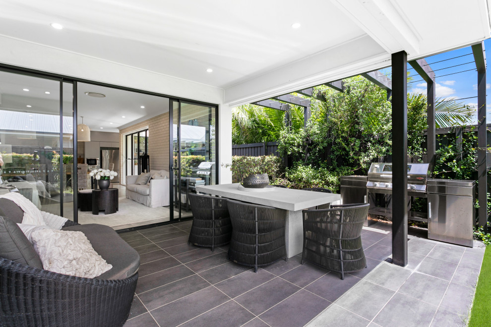 Photo of a small beach style backyard patio in Sunshine Coast with tile and an awning.