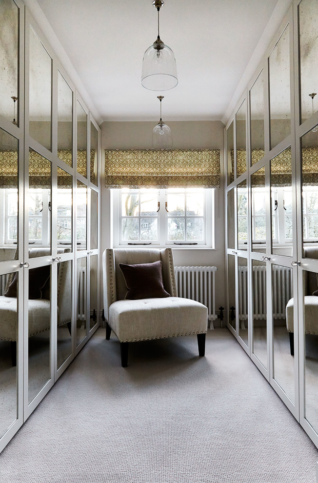 This is an example of a large classic walk-in wardrobe in London with recessed-panel cabinets, carpet and grey floors.