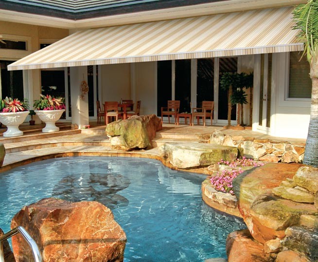 Mid-sized beach style backyard patio in Orange County with an awning and natural stone pavers.