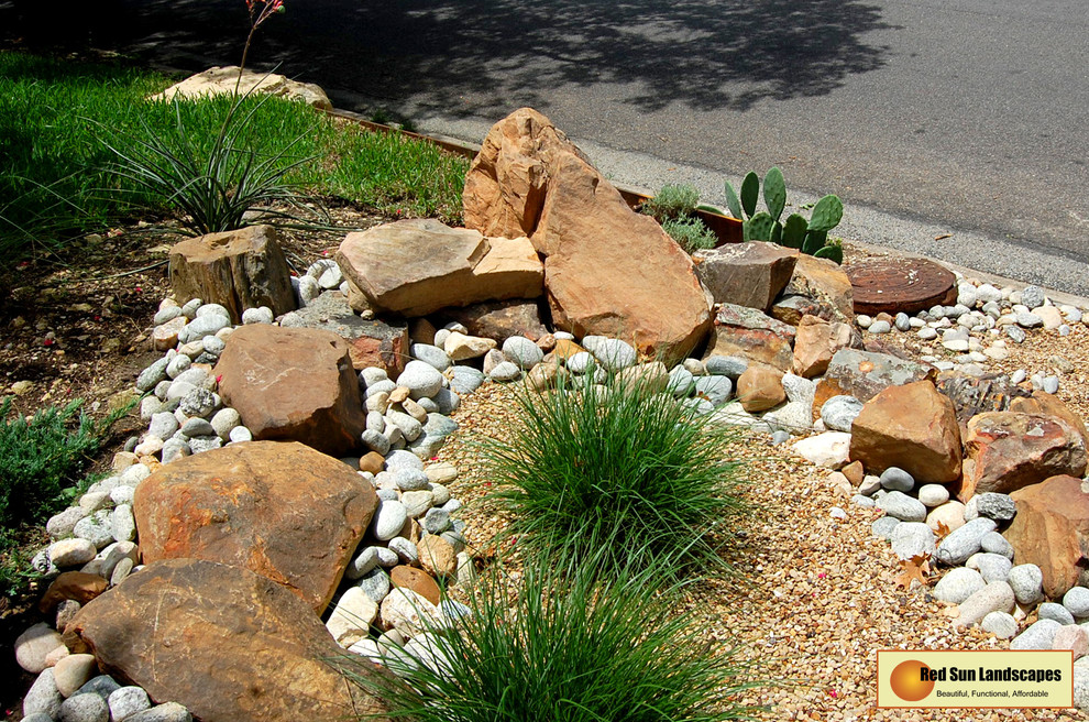 Large country sloped partial sun xeriscape with a retaining wall and natural stone pavers.