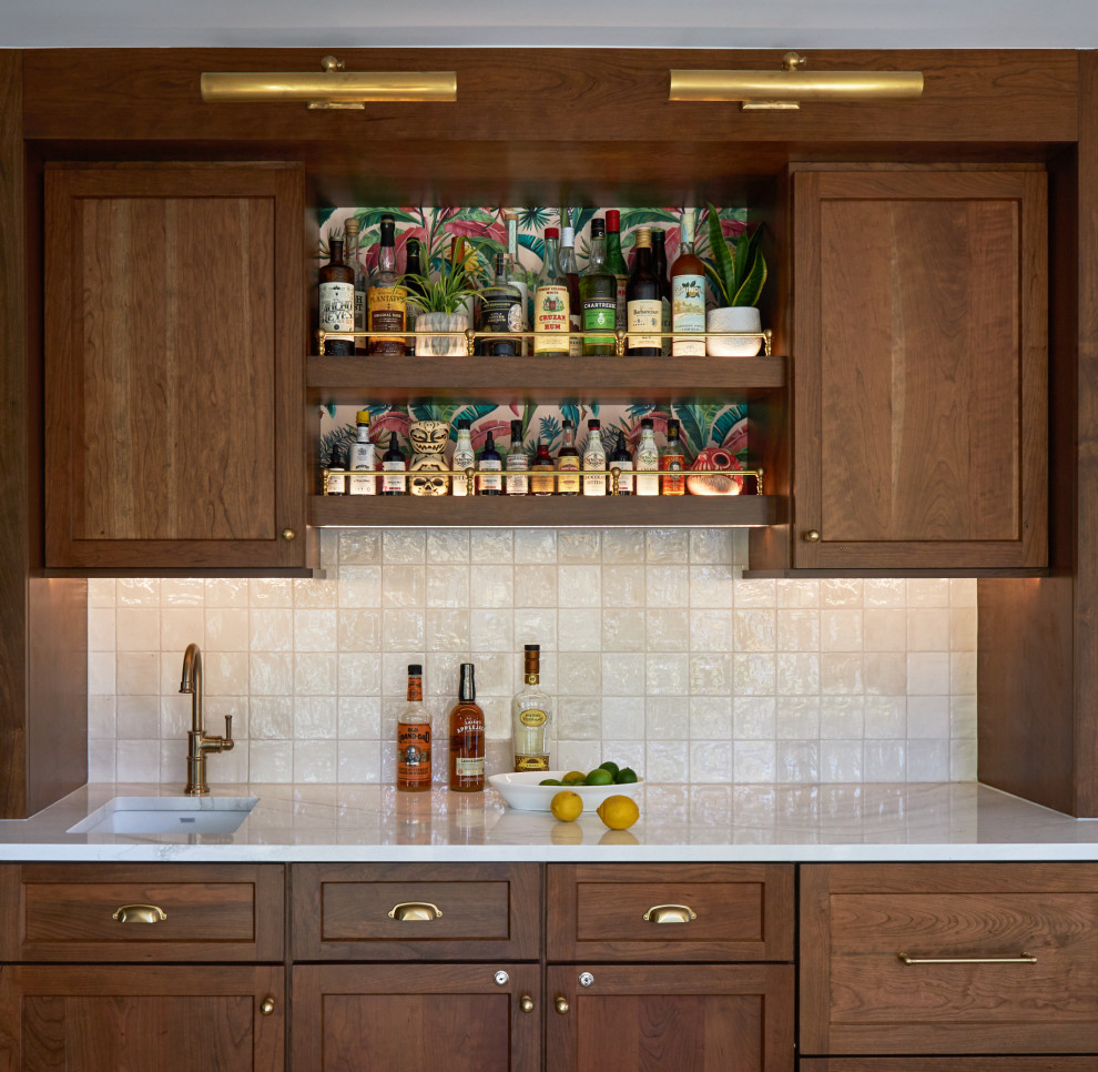 Small eclectic single-wall wet bar in Chicago with an undermount sink, shaker cabinets, medium wood cabinets, quartz benchtops, white splashback, ceramic splashback, light hardwood floors, brown floor and white benchtop.