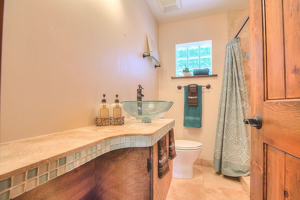 Photo of a small transitional master bathroom in Albuquerque with a vessel sink, flat-panel cabinets, dark wood cabinets, tile benchtops, a double shower, a two-piece toilet, beige tile, ceramic tile, white walls and travertine floors.