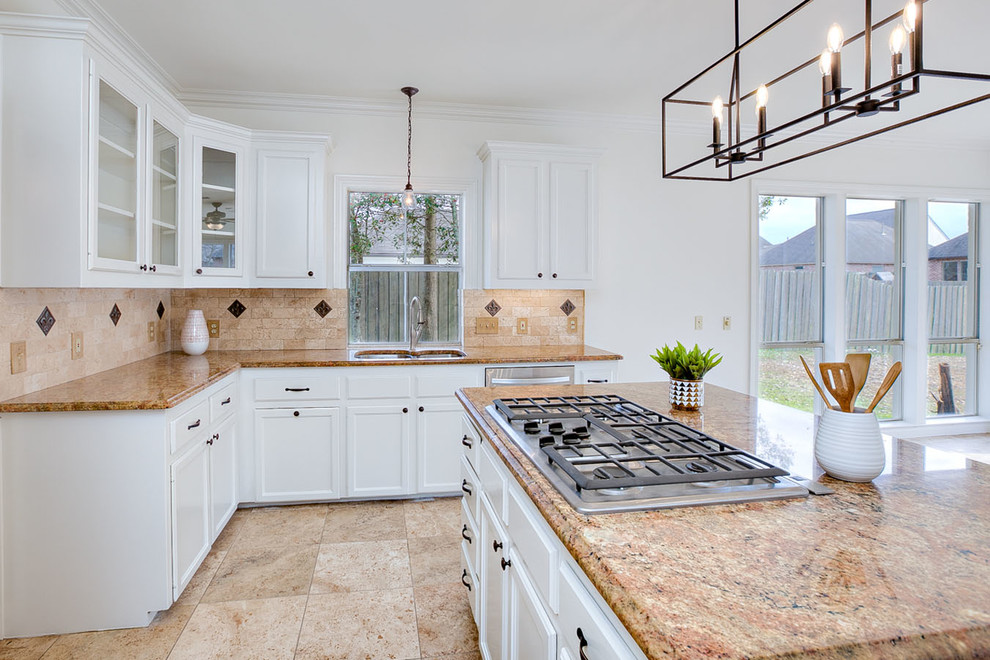 Design ideas for a mid-sized traditional u-shaped open plan kitchen in New Orleans with an undermount sink, raised-panel cabinets, white cabinets, granite benchtops, beige splashback, travertine splashback, stainless steel appliances, travertine floors, with island, beige floor and beige benchtop.