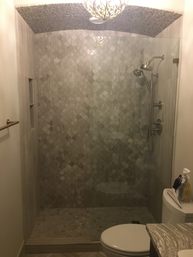 Photo of a mid-sized modern 3/4 bathroom in Austin with gray tile, grey walls, recessed-panel cabinets, grey cabinets, limestone floors, engineered quartz benchtops, an alcove shower, a two-piece toilet and limestone.