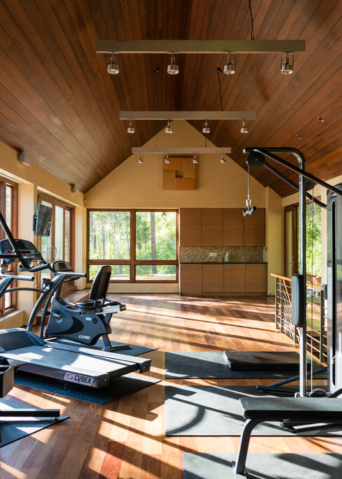 Home gym with various equipment in large room with wood ceiling