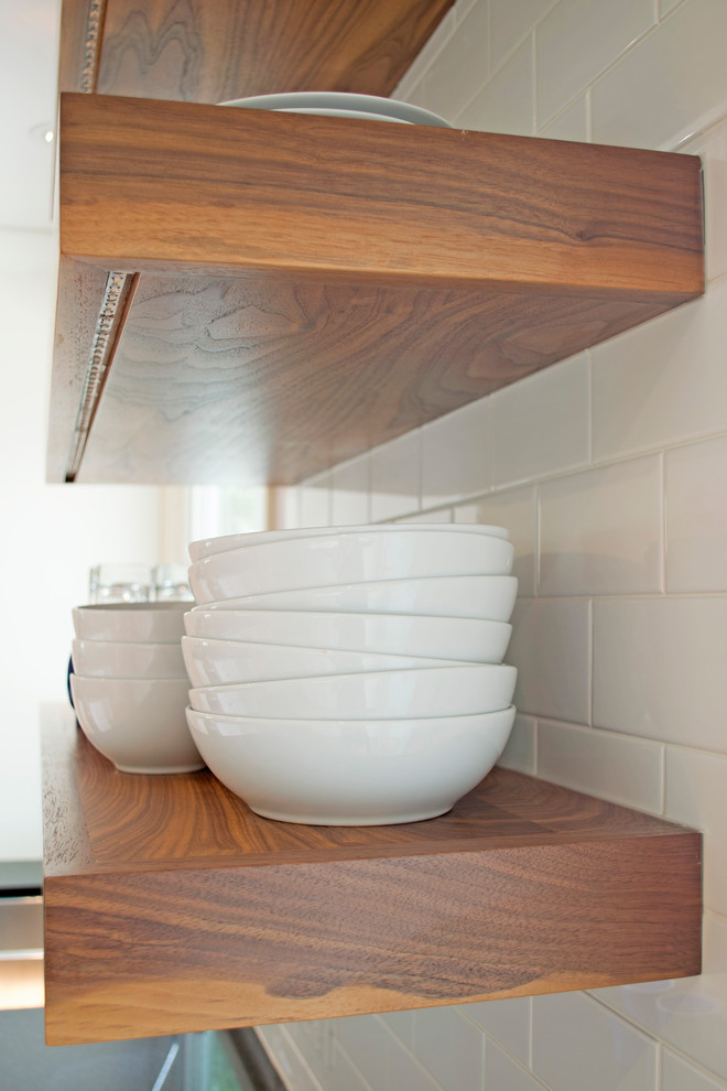 Example of a mid-sized transitional galley light wood floor home design design with an undermount sink, shaker cabinets, white cabinets, quartzite countertops, white backsplash, subway tile backsplash, stainless steel appliances, a peninsula and black countertops