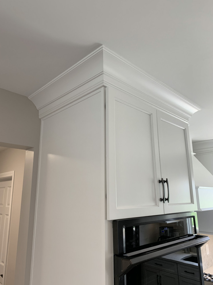 Example of a large transitional l-shaped vinyl floor and gray floor eat-in kitchen design with an undermount sink, recessed-panel cabinets, white cabinets, quartz countertops, gray backsplash, ceramic backsplash, stainless steel appliances, an island and white countertops