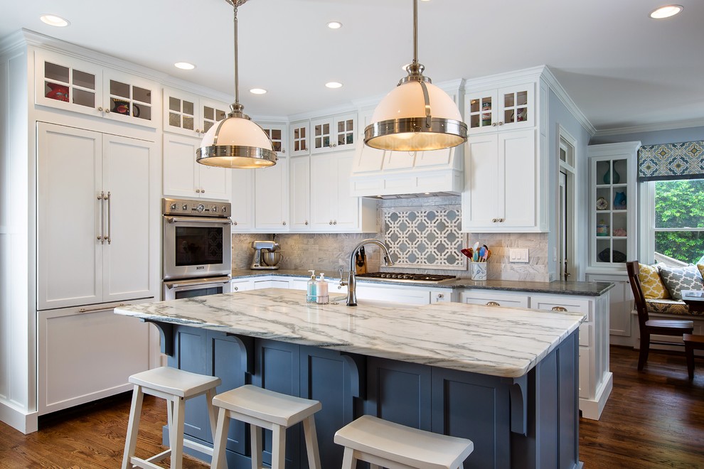 Photo of a large transitional l-shaped eat-in kitchen in Atlanta with a farmhouse sink, shaker cabinets, white cabinets, soapstone benchtops, white splashback, stone tile splashback, stainless steel appliances, medium hardwood floors and with island.