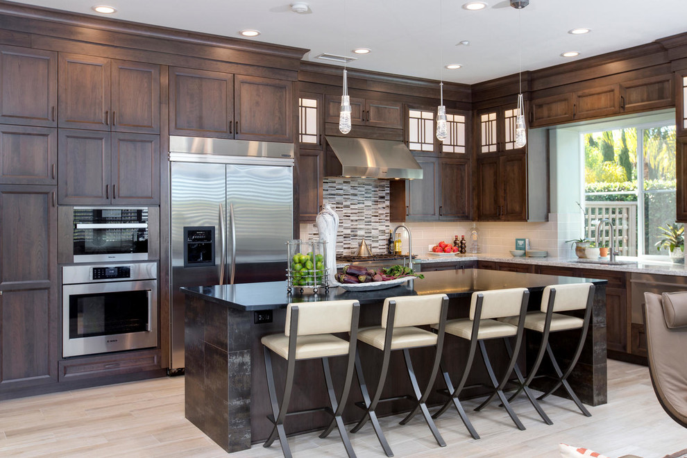 Example of a large transitional l-shaped porcelain tile and beige floor open concept kitchen design in Denver with an undermount sink, recessed-panel cabinets, dark wood cabinets, soapstone countertops, gray backsplash, glass sheet backsplash, stainless steel appliances, an island and white countertops