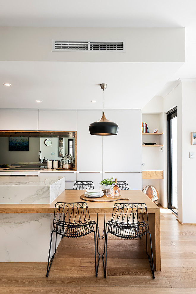 Idéer för ett stort modernt vit linjärt kök med öppen planlösning, med en dubbel diskho, släta luckor, vita skåp, kaklad bänkskiva, stänkskydd med metallisk yta, spegel som stänkskydd, svarta vitvaror, ljust trägolv, en köksö och brunt golv