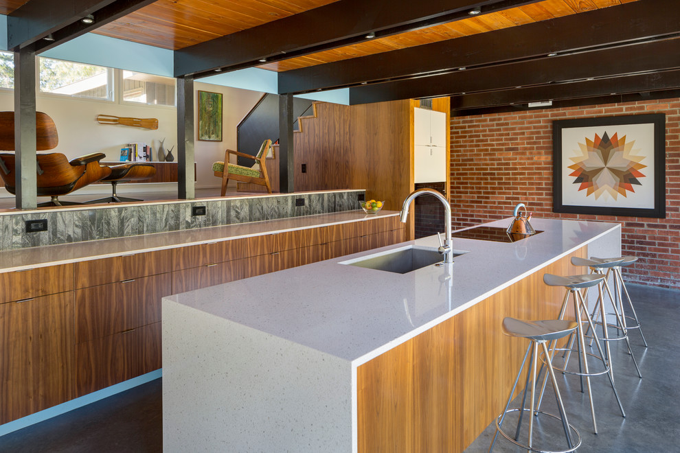 Photo of a midcentury galley kitchen in Kansas City with an undermount sink, flat-panel cabinets, medium wood cabinets, concrete floors and with island.