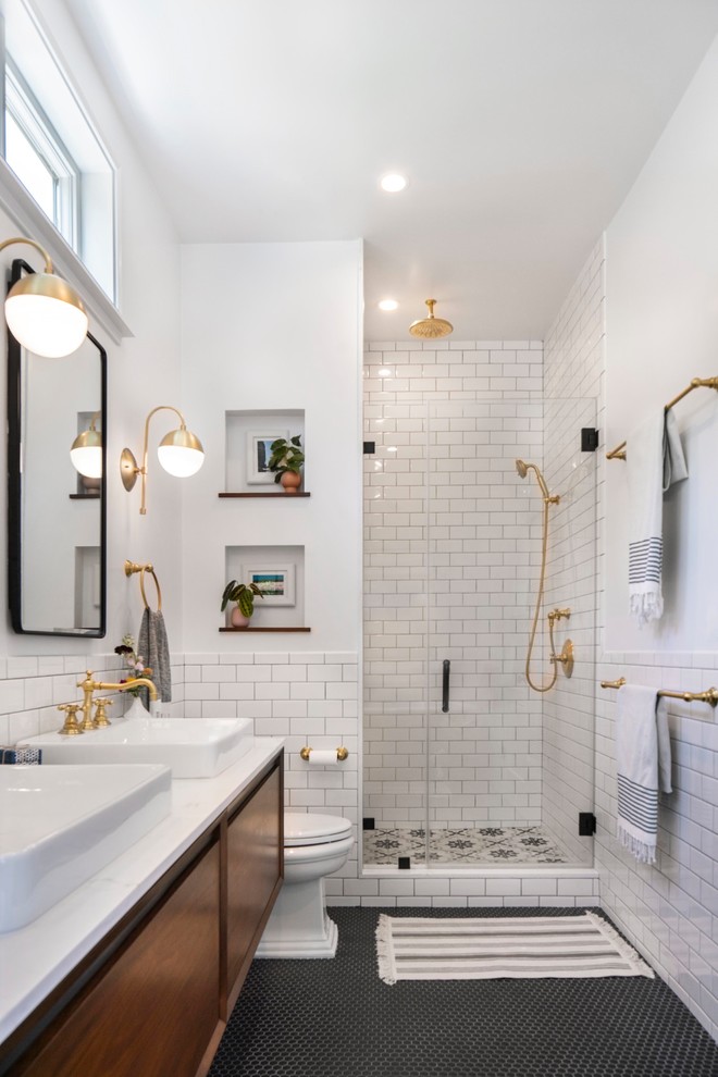 Example of a mid-sized transitional master white tile and ceramic tile mosaic tile floor and black floor alcove shower design in Los Angeles with flat-panel cabinets, white walls, a vessel sink, quartz countertops, a hinged shower door, white countertops and medium tone wood cabinets