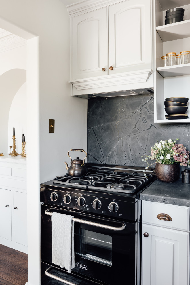 Small transitional kitchen in Salt Lake City with black splashback, black appliances, black benchtop, raised-panel cabinets, white cabinets, stone slab splashback and dark hardwood floors.