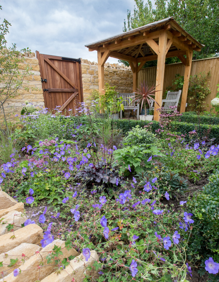 Uriger Garten im Sommer, hinter dem Haus mit Natursteinplatten und Holzzaun in Sonstige