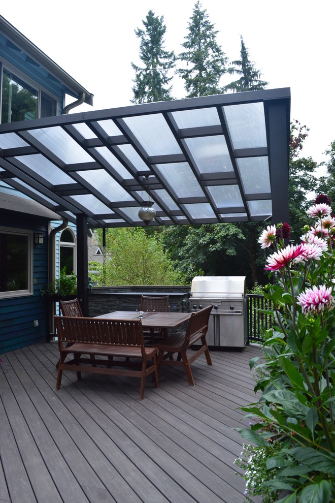 This is an example of a mid-sized eclectic backyard deck in Seattle with an outdoor kitchen and an awning.