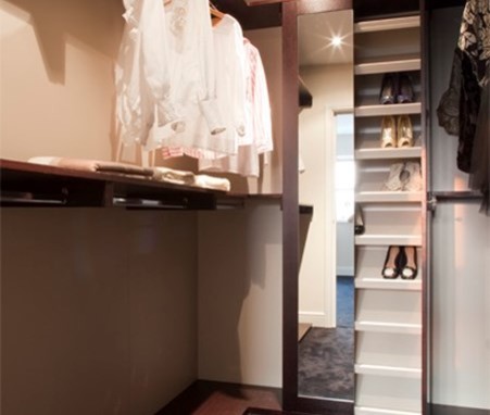This is an example of a contemporary gender neutral walk-in wardrobe in London with open cabinets and dark wood cabinets.