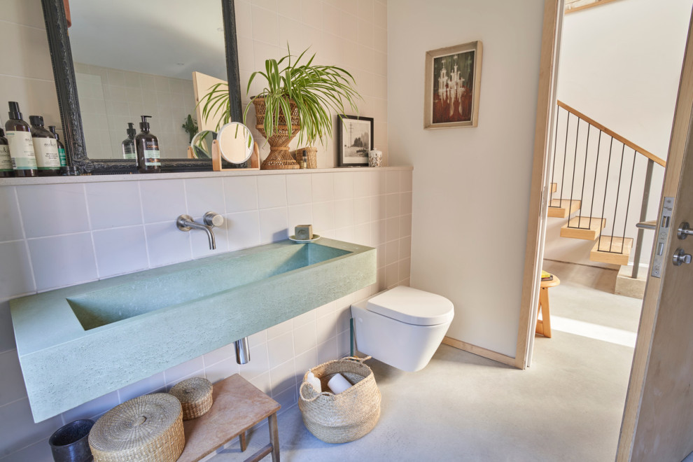 Medium sized scandi family bathroom in Kent with a built-in bath, a shower/bath combination, a wall mounted toilet, pink tiles, ceramic tiles, concrete flooring, a wall-mounted sink, concrete worktops, grey floors, green worktops and double sinks.