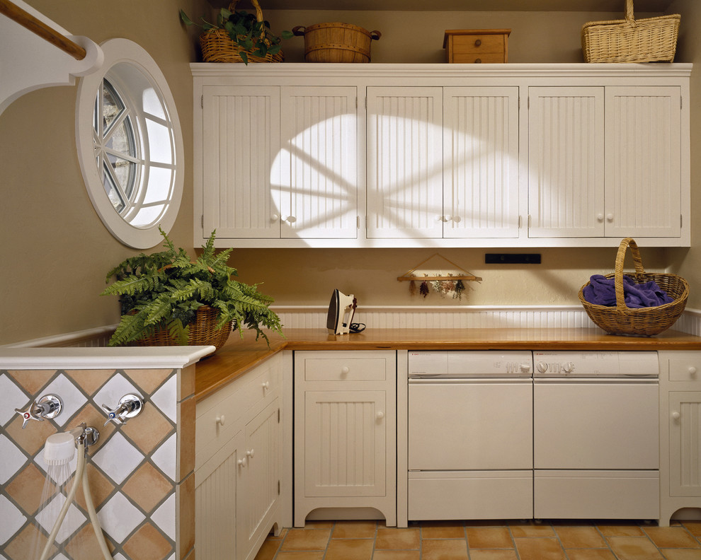 This is an example of a traditional laundry room in New York with white cabinets.