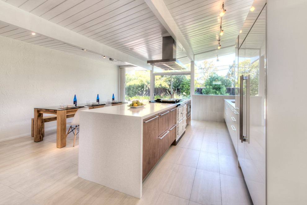 Inspiration for a mid-sized transitional single-wall porcelain tile eat-in kitchen remodel in Nice with a single-bowl sink, flat-panel cabinets, white cabinets, solid surface countertops, white backsplash, porcelain backsplash, paneled appliances and an island