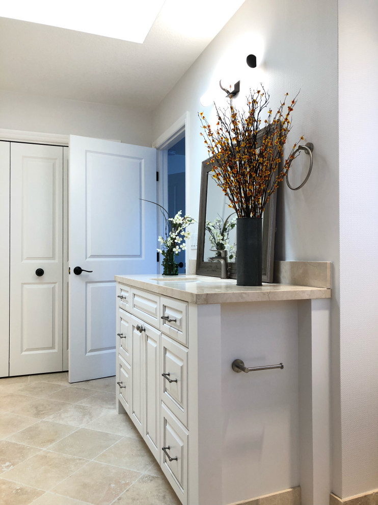 Photo of an expansive transitional bathroom in Other with raised-panel cabinets, white cabinets, white walls, travertine floors, an undermount sink, quartzite benchtops, beige benchtops, a single vanity and a freestanding vanity.