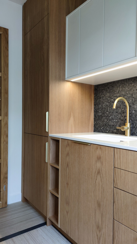 Inspiration for a small contemporary galley enclosed kitchen in Other with a submerged sink, beaded cabinets, light wood cabinets, quartz worktops, black splashback, slate splashback, integrated appliances, ceramic flooring, beige floors and white worktops.