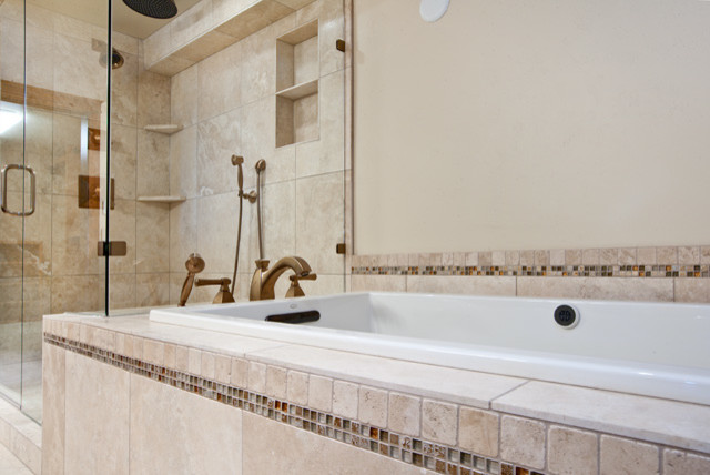 Traditional bathroom in Denver with a drop-in tub and stone tile.