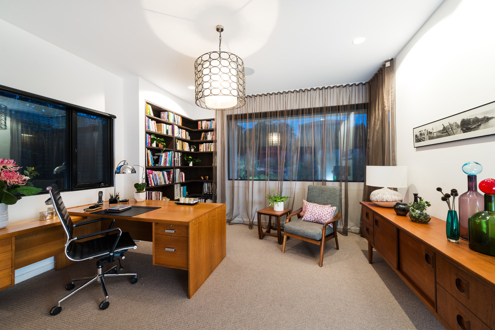 Photo of a midcentury study room in Melbourne with white walls, carpet, a freestanding desk and brown floor.