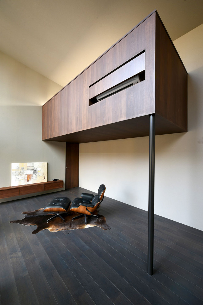 Diseño de despacho gris retro de tamaño medio con paredes grises, suelo de madera oscura, estufa de leña, marco de chimenea de metal, escritorio empotrado, suelo negro y madera