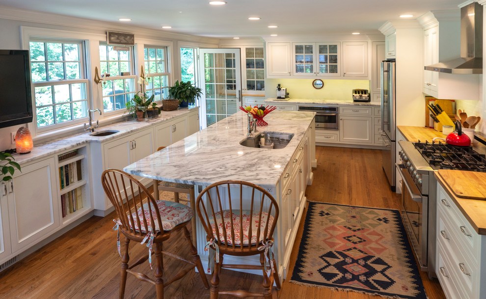 Eat-in kitchen - large transitional medium tone wood floor and brown floor eat-in kitchen idea with an undermount sink, flat-panel cabinets, white cabinets, quartzite countertops, white backsplash, ceramic backsplash, stainless steel appliances, an island and white countertops